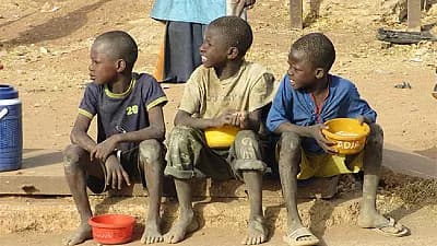 Three children the Human Ego Transformation Foundation supports, sitting together outside with their bowls.