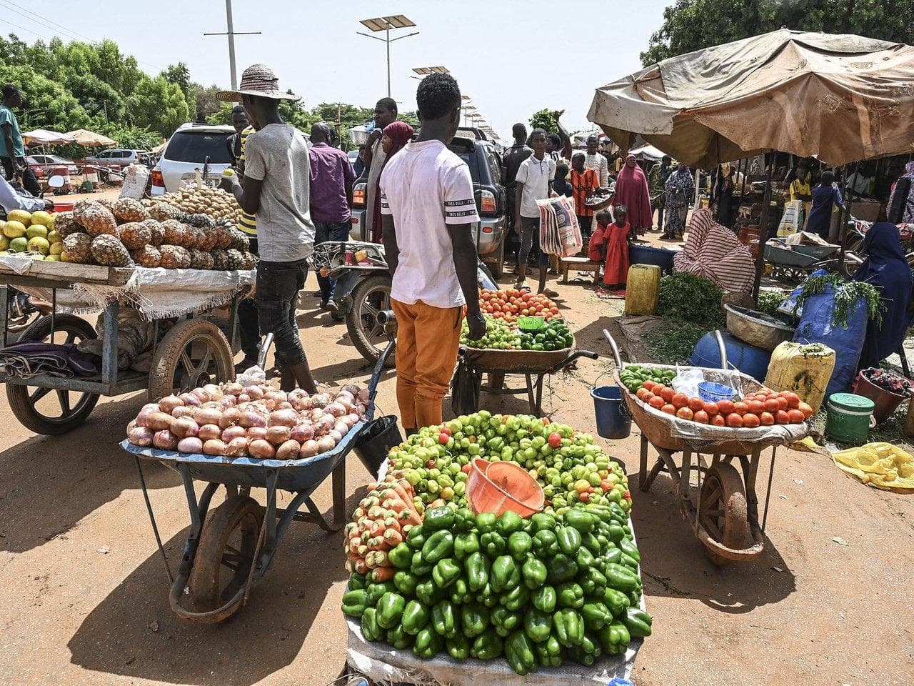 Vendors selling fresh produce at a busy open-air market.
